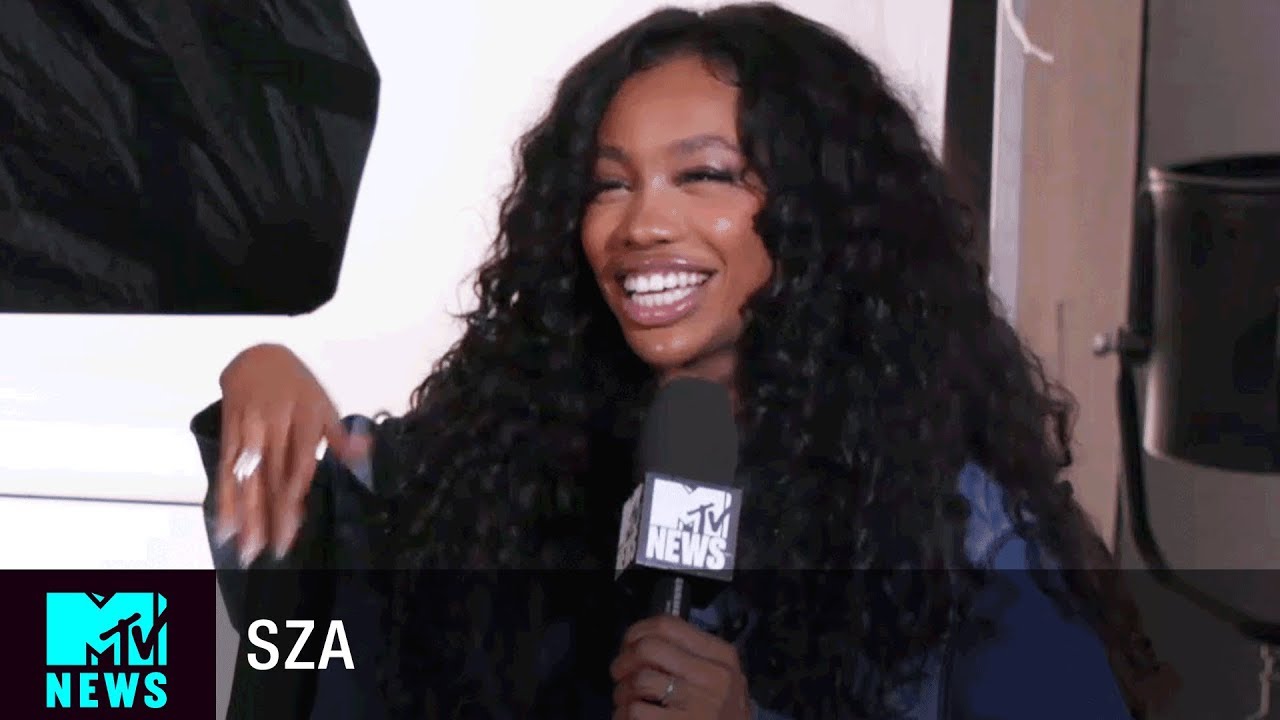 SZA's interview on MTV,SZA in a denim jacket, open hair holding a mic